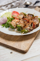 Appetizer kebabs in skewers in a plate on a wooden board