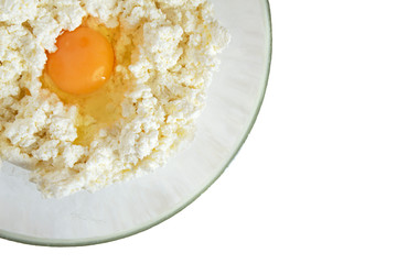 Cottage cheese and egg in a glass bowl isolated on a white background. The process of making cheese pancakes