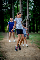 School children in white t shirts skipping ropes at public park