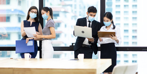Young businesswoman and business man wearing protective face mask while meeting for making new business plans during COVID-19 pandemic