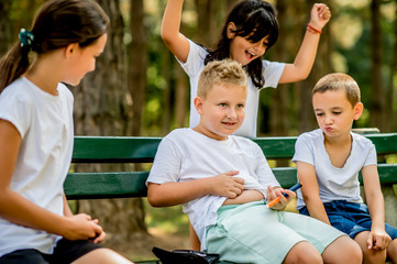 School boy with diabetes testing his blood sugar after physical education, friends support him.