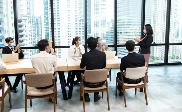 Young businesswoman and business man wearing protective face mask while meeting for making new business plans during COVID-19 pandemic