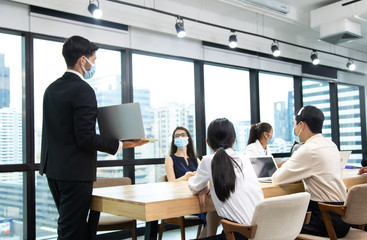 Young businesswoman and business man wearing protective face mask while meeting for making new business plans during COVID-19 pandemic