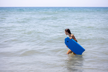 A girl carrying a bodyboard on the beach
