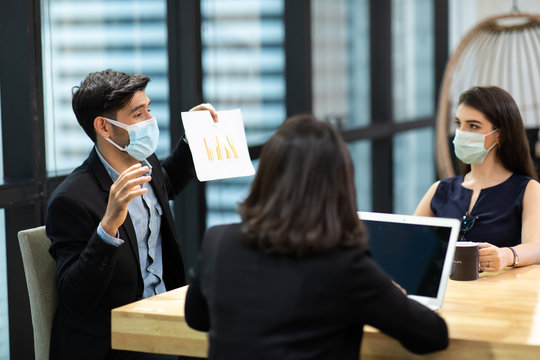 Young businesswoman and business man wearing protective face mask while meeting for making new business plans during COVID-19 pandemic