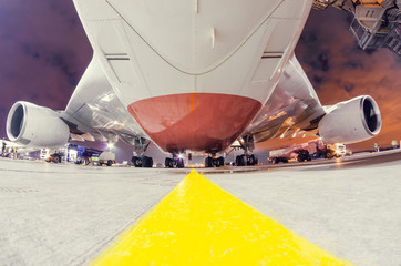 View of a huge wide-body aircraft from below, along the yellow stripe.