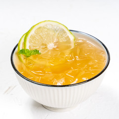 Taiwanese food - delicious cold drinking dessert Aiyu ice jelly in a white bowl and background with green lemon and mint topping, close up.
