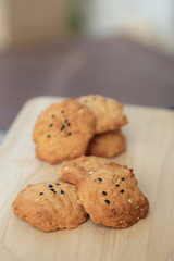 Tasty sesame cookies on wooden plate.