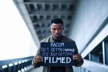 Man with written sign standing outdoors, black lives matter concept.