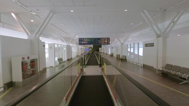 This is a handheld slow mo shot standing in a moving walkway in a uncrowded Kuala Lumpur Airport.