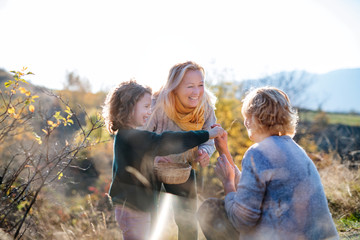 Fototapeta premium Small girl with mother and grandmother collecting rosehip fruit in autumn nature.