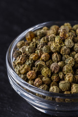 green peppercorns on dark slate stone background