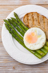 Asparagus with scrambled eggs and buckwheat on a plate, top view