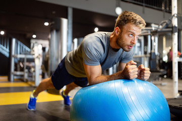 Fototapeta na wymiar Fit man doing fitness exercise on pilates ball in gym