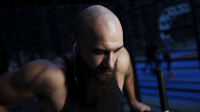 Young Guy With Beard And Ear Piercing Goes In For Sports. He Trains On Sports Simulator.