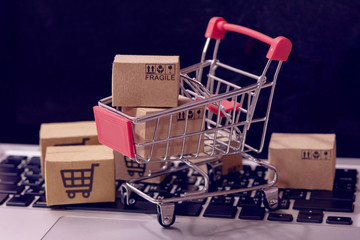 Shopping online. cardboard box with a shopping cart logo in a trolley on laptop keyboard. Shopping...