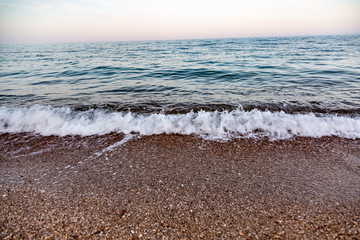 The sea waves against the pebble shore. Close-up. Horizon. Horizontal orientation. 