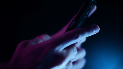 Hand using a smart phone in close up on a black background	
