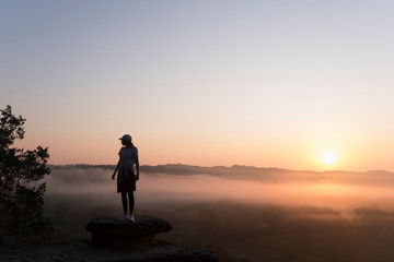 Silhouette of Girl hiking on mountain top at sunrise