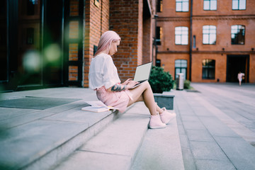 Side view of skilled remote worker searching application for making banking payment and buy online education courses, millennial female student browsing website on mockup laptop with copy space area