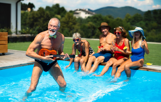 Group of cheerful seniors by swimming pool outdoors in backyard, party concept. - Powered by Adobe