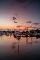 Predawn at the marina with sailboats at the dock in calm water.