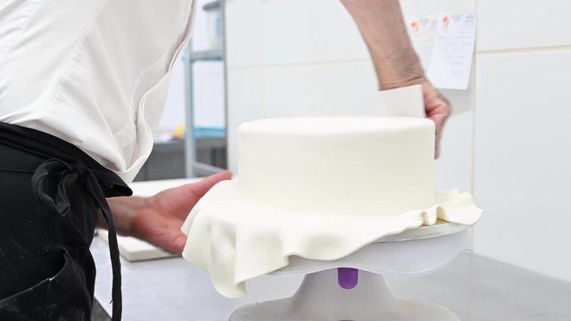 Confectioner decorating a wedding cake with white fondant . High quality 4k footage