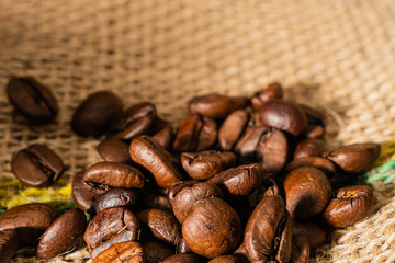 primer plano de granos de cafe tostados sobre tela de bolsa de arpillera