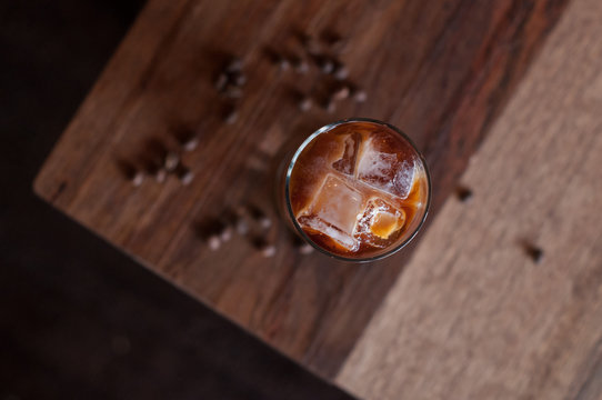 Tall Glass of cold brew iced coffee on a wooden coffee table