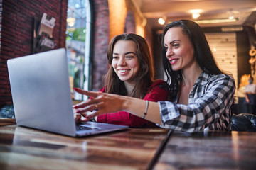 Casual happy smiling mother and daughter watching together video content on a laptop and having...