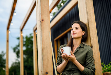 Young woman outdoors, weekend away in container house in countryside.