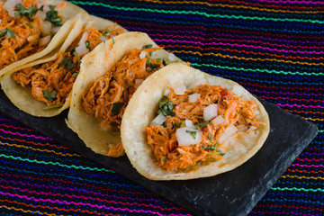 Mexican tacos filled with tinga de pollo on a traditional textile background