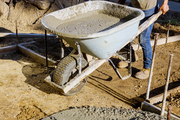 Construction worker pushing wheelbarrow with concrete at building