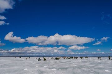 group of fishermen fishing on the ice pond