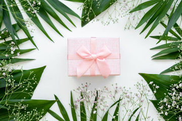 Holiday present. Floral composition. Pink gift box with ribbon bow in green leaf frame isolated on white. Natural arrangement. Festive background.