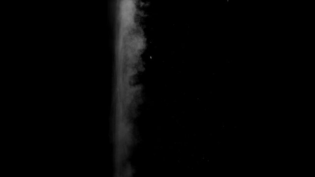 Dusty bullet hits on a wall with chunks of debris flying out . Powder explosion on black background. Impact dust particles. Dust explosion in front of black background, slow-motion close up. VFX

