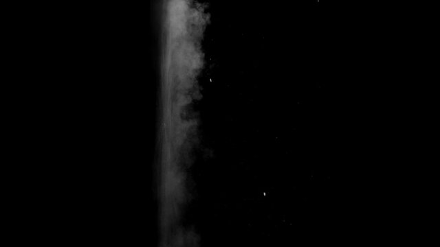 Dusty bullet hits on a wall with chunks of debris flying out . Powder explosion on black background. Impact dust particles. Dust explosion in front of black background, slow-motion close up. VFX