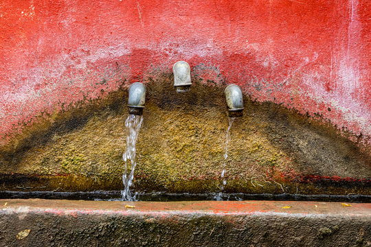 three village fountain on red and green wall. village life