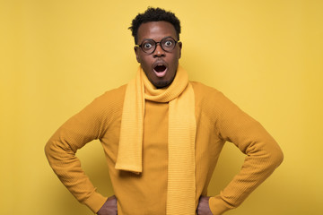 African man in yellow sweater and scarf with shocked emotional facial expression