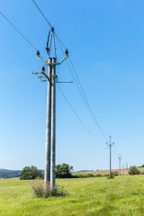 Obraz premium Energy concept. High voltage pole power lines against the blue clear sky. Electric poles in the rural landscape of the Czech Republic