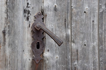 Rostiger antiker Türbeschlag auf grauem verwittertem Holz