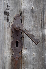Rostiger antiker Türbeschlag auf grauem verwittertem Holz