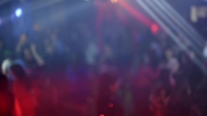 crowd of people dancing on the dance floor of a night club under the light of colored spotlights and lasers