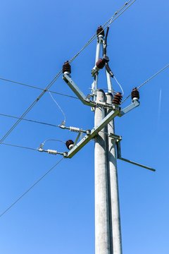 Energy concept. High voltage pole power lines against the blue clear sky. Three-phase power line to turn. Electricity distribution.