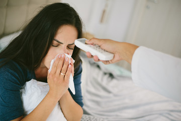 High angle shot of a female getting her fever checked by a nurse with a digital thermometer.