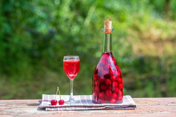 Homemade tincture of red cherry. Berry alcoholic drinks concept. Red wine made in a glass bottle...