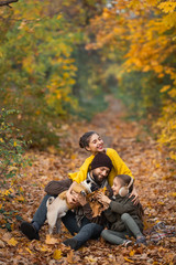 bearded dad with daughters and a dog in the leaves in autumn in the park