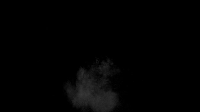 Dusty bullet hits on a wall with chunks of debris flying out . Powder explosion on black background. Impact dust particles. Dust explosion in front of black background, slow-motion close up. VFX
