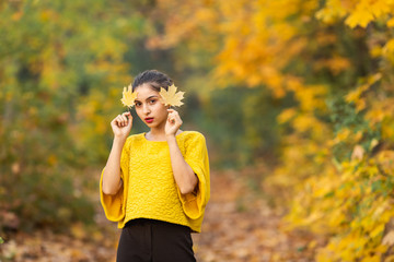 Cheerful woman portrait with autumn maple leaves in the park