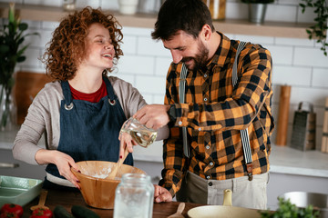 Boyfriend and girlfriend making delicious food at home. Loving couple cooking in kitchen..